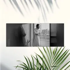 A thoughtful black and white portrait of the groom looking out a window. The natural light and shadows create a contemplative and cinematic mood.