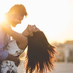 A candid and carefree pre-wedding shot, capturing a couple's laughter and movement against the warm, golden light of the setting sun.