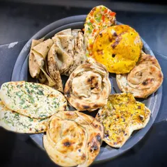 A platter showcasing the incredible variety of my handcrafted Indian breads. Each one, from the flaky parathas to the soft naans, is made fresh for your event.