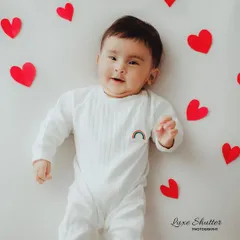 A simple and lovely milestone photo for a five-month-old, lying on a white background surrounded by red paper hearts.
