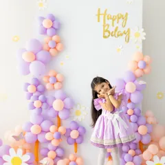 A playful pose to celebrate her special day. The custom balloon backdrop in her favorite colors makes this birthday photoshoot feel personal and fun.