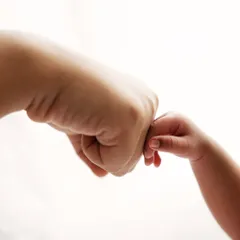 A tiny fist bump. A playful and sweet way to capture the bond between a parent and their new little buddy.