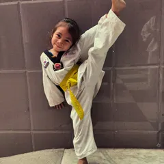 This young girl with a yellow belt shows off her high kick and a big smile. This is what girl power and dedication look like.