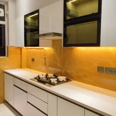 Luxury at its best. This stunning kitchen features white high-gloss cabinets, a vibrant yellow onyx backsplash with backlighting, and a clean, white countertop. The design is both bold and incredibly elegant.
