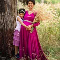 An outdoor maternity portrait capturing a tender moment between a mother and her daughter. Set in a natural field, the mother holds a bouquet of wheat, symbolizing growth and new life.