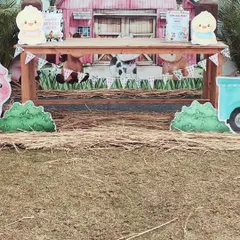 The main cake table setup for the farm party. A rustic wooden table is set in front of the barn backdrop, with hay bales and animal cutouts creating a complete barnyard scene.