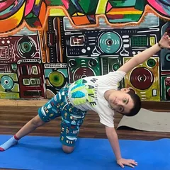 This young student is holding a side plank pose with great form and a smile. Our kids' yoga classes are designed to build strength in a playful way.
