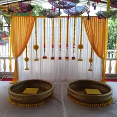 A closer look at the seating area for the Haldi ceremony, featuring two large 'urli' pots for the bride and groom, decorated with marigold flowers.