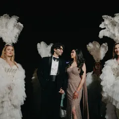 We create theatrical and memorable portraits that match the vibe of your event. Here, the couple is framed by performers in feathered costumes, adding a touch of old-world glamour and spectacle to their engagement photos.