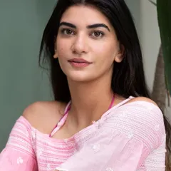 A simple, natural headshot of a model wearing a pink off-the-shoulder top. This portrait highlights a fresh, summery look that complements a beach or resort wear collection.