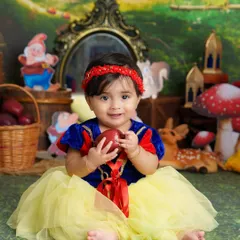Mirror, mirror on the wall, who is the cutest of them all? This little Snow White, holding an apple in her enchanted forest, is a perfect fairytale princess.