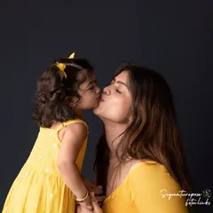 A sweet kiss between mother and daughter. This intimate and tender moment is what makes these "Mom & Me" sessions so special, creating a timeless portrait of their bond.