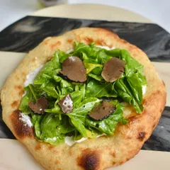 Our Truffle Sourdough Flatbread was a huge hit at our Spanish popup. It's topped with creamy cheese, fresh arugula, and shaved black truffle for an earthy, decadent flavour.