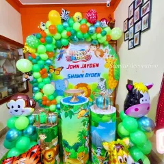 A bright and lively jungle theme for a joint birthday party. This decoration is packed with details, including a custom backdrop, themed pedestals for cakes, and lots of animal foil balloons like monkeys, tigers, and zebras.