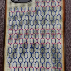 A finished phone insert, ready to be placed in a transparent case. This one features a geometric pattern in blue and pink, a modern take on counted thread embroidery.