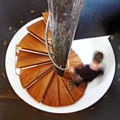 A spiral staircase becomes a sculptural element, with fanning wooden treads supported by a central textured column. I design circulation as an experience, exploring how light and materials can turn movement into a moment of beauty.