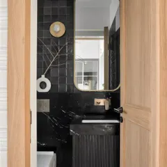 This study bathroom is a personal favorite. It features dramatic black square tiles and Brazilian black marble on the walls, contrasted with white rustic floor tiles. Brushed gold Kohler faucets add a final touch of drama.