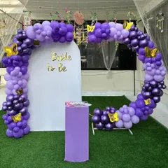 A cute 'Bride to be' photo corner with a purple balloon arch accented with golden butterflies, perfect for a fun bachelorette party.