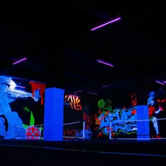 Another perspective of the Level One Arena under UV light. The artwork covers multiple walls, ensuring that the entire space is filled with glowing, dynamic art that enhances the gaming and sporting experience.