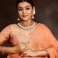 A closer look at the peach lehenga, showing the subtle texture of the fabric and how it pairs with delicate jewelry for a soft, romantic look.