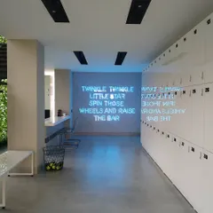 The locker and hallway area of the studio, featuring a custom neon sign with a motivational quote. This element adds a playful and branded touch to a functional space, enhancing the overall member experience.