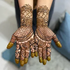 This design is filled with detail, combining delicate star-like nets (jaali) on the palm with bold floral work on the fingers and wrists. The covered fingertips add to the traditional bridal feel.