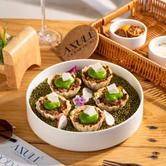 Creative canapés served on a bed of green lentils. The unique presentation makes this dish stand out.
