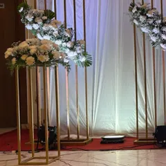 Minimalist and modern decor featuring tall, slender golden stands with simple white floral arrangements, perfect for an elegant and understated event.
