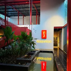 The architecture of the SARITHA SERENE office is designed to be open and interconnected. The red steel structure is a dominant visual theme, unifying the different levels and drawing the eye through the space, from the water feature to the upper floors.
