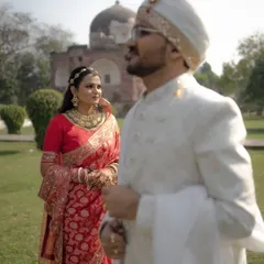A beautifully composed shot with the bride in sharp focus, looking towards her groom who is softly blurred in the foreground, set against a historic monument.