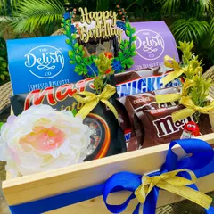 The 'Birthday Goodness' hamper is a chocolate lover's delight. This wooden tray is packed with Espresso Biscotti, Red Velvet Cookies, Mars, Snickers, and M&M's, topped with a 'Happy Birthday' sign.