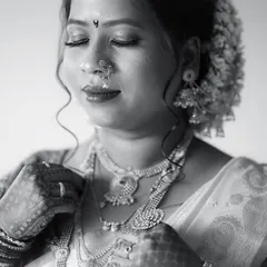 A classic monochrome portrait of a bride. The black and white tones emphasize the rich textures of her jewelry and the serene emotion on her face.