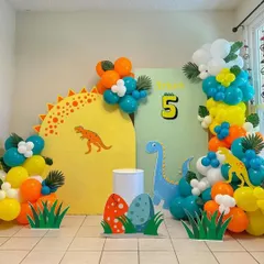 A bright and colorful dinosaur theme for a 5th birthday. This setup includes vibrant balloon garlands, dinosaur cutouts, and themed backdrop panels.