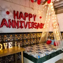 This cozy and romantic anniversary room decoration features a canopy of fairy lights over the bed. I also added 'Happy Anniversary' foil balloons, ceiling balloons, and a light-up 'LOVE' sign to complete the intimate setting.