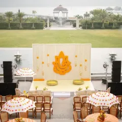 A traditional Haldi setup at Raffles Udaipur, with a backdrop featuring a Ganesha made of marigolds. The seating with custom-printed umbrellas adds a touch of local artistry.