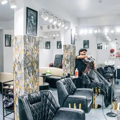 Our salon floor is designed to be open and comfortable. Here you can see one of our stylists working on a client's hair, with our modern styling chairs and well-lit stations.