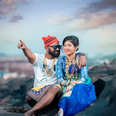 A playful and candid shot from an Agri-Koli pre-wedding session. The groom points out towards the sea, sharing a happy moment with his bride, showcasing their joyful connection against a scenic coastal background.