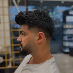 This is a great example of how a fade and beard can work together. The hair fades down to the skin and then blends back into the full, well-defined beard for a strong, masculine style.
