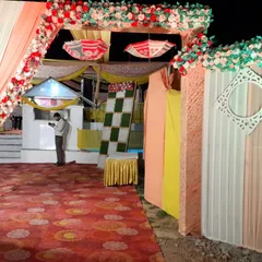 Your guests' first impression matters. We design beautiful and welcoming entrances, like this one featuring a colorful floral arch, traditional decorative umbrellas, and flowing drapes to set a festive tone for the wedding celebration.