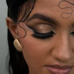 A detailed close-up of the eye makeup, showing the combination of a sharp black wing, a parallel white graphic line, and a pop of gold glitter for a touch of glam.