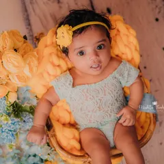 Sitting up like a pro in her little basket. The combination of yellow and blue flowers adds a beautiful, soft touch to this milestone photo.