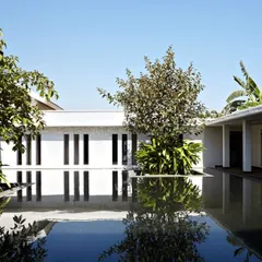 The serene courtyard of the spa at Club Mahindra, Lake Pawana. The design uses water as a reflective surface to amplify the sense of peace, with minimalist white colonnades and strategically placed greenery creating a tranquil, enclosed world for relaxation.