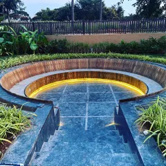 The combination of stone, wood, and light in this seating area creates a sophisticated and modern hardscape feature.