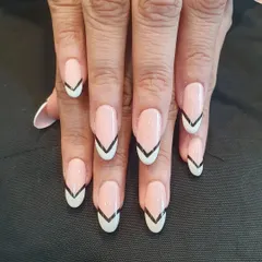 A graphic and modern take on the French manicure. This design on almond-shaped nails uses a sharp, black V-shape to outline the white tip, creating a bold and edgy look.