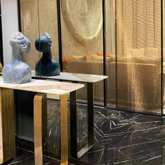 A close-up of a console table arrangement. This detail shot highlights the contrast between the black marble floor, the brushed gold legs of the table, and the sculptural art pieces, showcasing our focus on material and form.