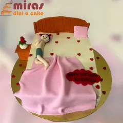 A funny and personalized cake showing a person relaxing in bed. This sculpted cake is a playful nod to someone who loves their comfort, complete with a tiny rose on the nightstand.