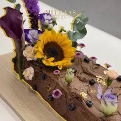 This 6kg decadent chocolate log cake was created for a baby shower, designed to feel like a piece of an enchanted forest. It's decorated with fresh blueberries, edible butterflies, and a beautiful arrangement of fresh, seasonal flowers.