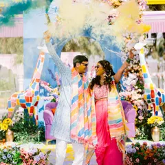 A blast of color! Laxmi and Roshan are framed by yellow and blue smoke, creating a dynamic and unforgettable image from their Haldi celebration.