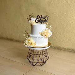 A classic two-tier "Just Engaged" cake, elegantly decorated with white roses and gold leaf accents. We teach techniques for applying gold leaf for that touch of luxury.