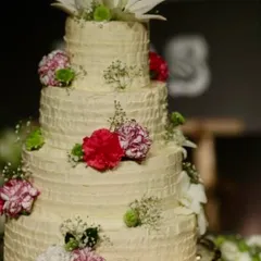 This four-tiered rustic wedding cake with textured buttercream and fresh flowers is a testament to our elegant and delicious approach. We believe in the beauty of natural ingredients and skilled craftsmanship.